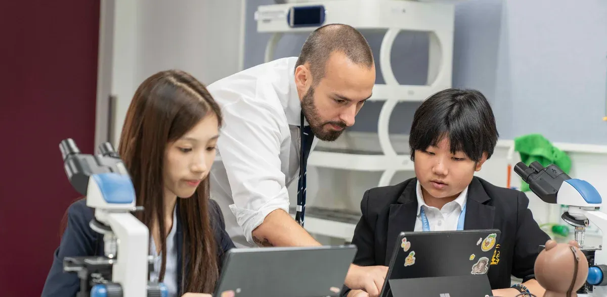 A Wellington College International Tianjin teacher assisting two senior school students with their research work, exemplifying the school's commitment to guiding international students towards top university destinations