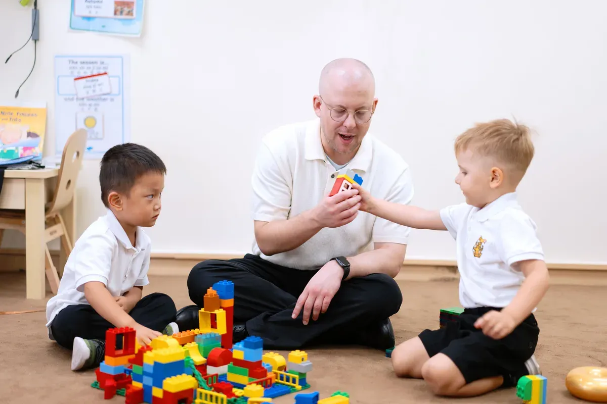 Two Early Years pupils engage in play with building blocks alongside a teacher at Wellington College International Tianjin, an international school in China. 